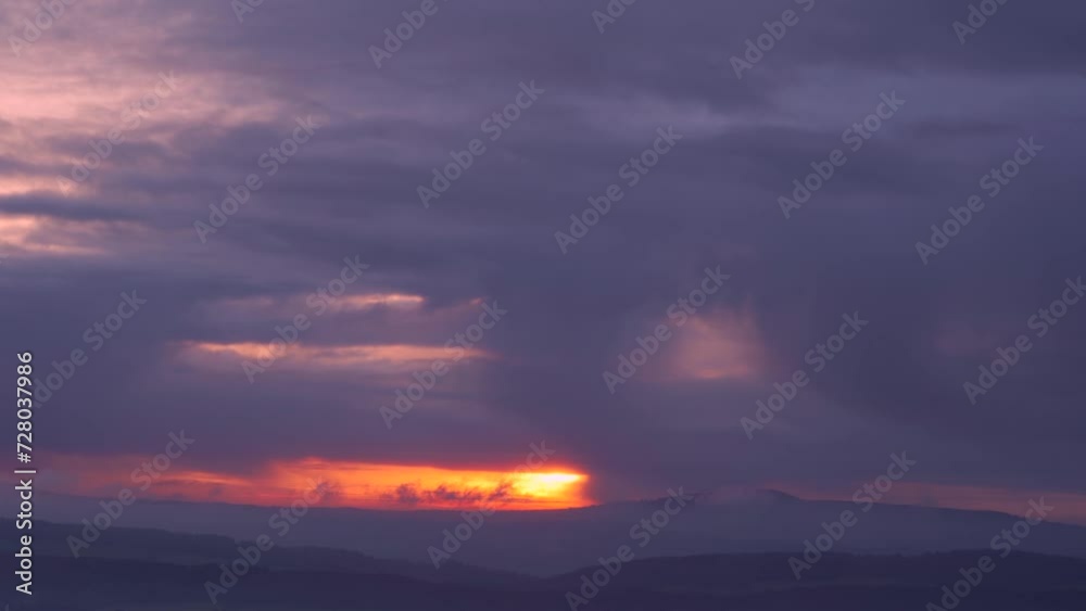 A magical sunrise moment with fiery red sunlight breakign through gaps above the English countryside A magical sunrise moment with fiery red sunlight breakign through gaps above the English countryside