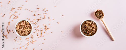 Raw buckwheat tea in a bowl and wooden spoon and buckwheat on the table top view web banner photo