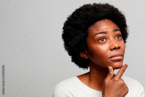 Woman looking up in thought finger on chin.