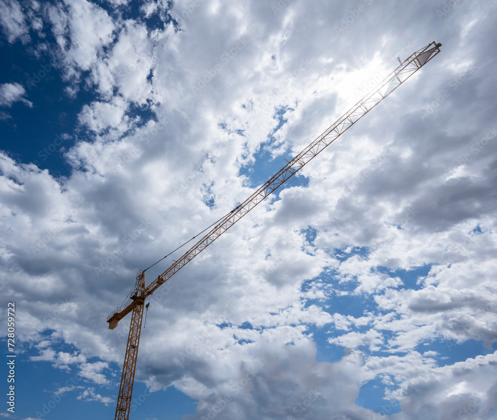 Towering crane extending into a cloudy sky, symbolizing growth.