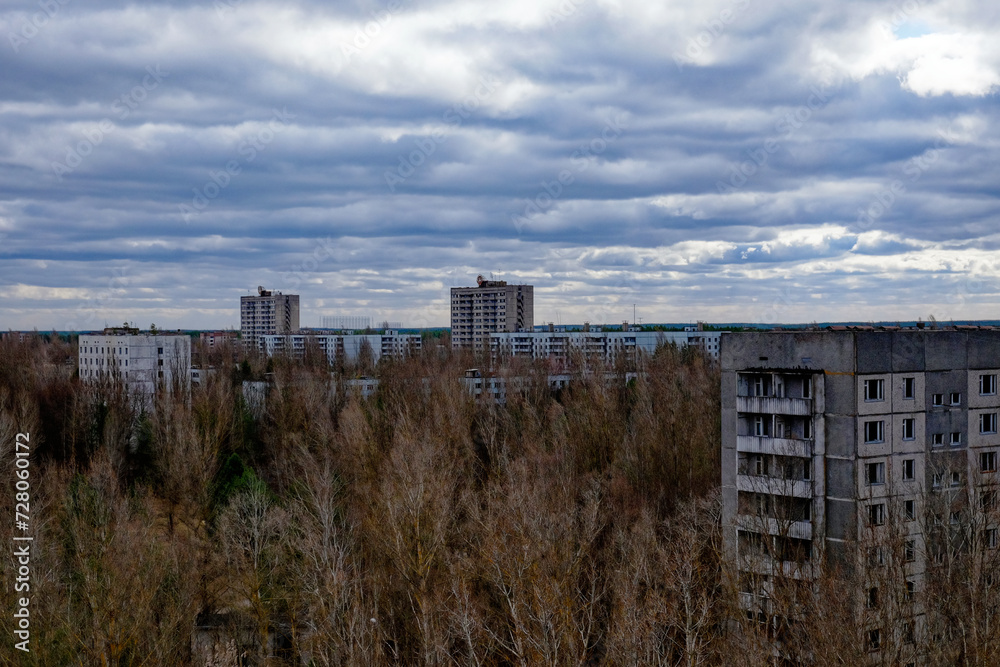 The image captures old apartments amidst bare trees under an ominous cloud-covered sky.