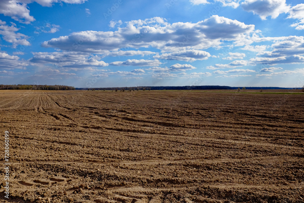 A barren landscape with ploughed earth and cloudy skies.