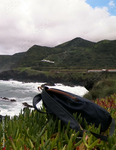 Rucksack on cliffs at Piscinas Naturais Caneiros, travel and nature concept. photo