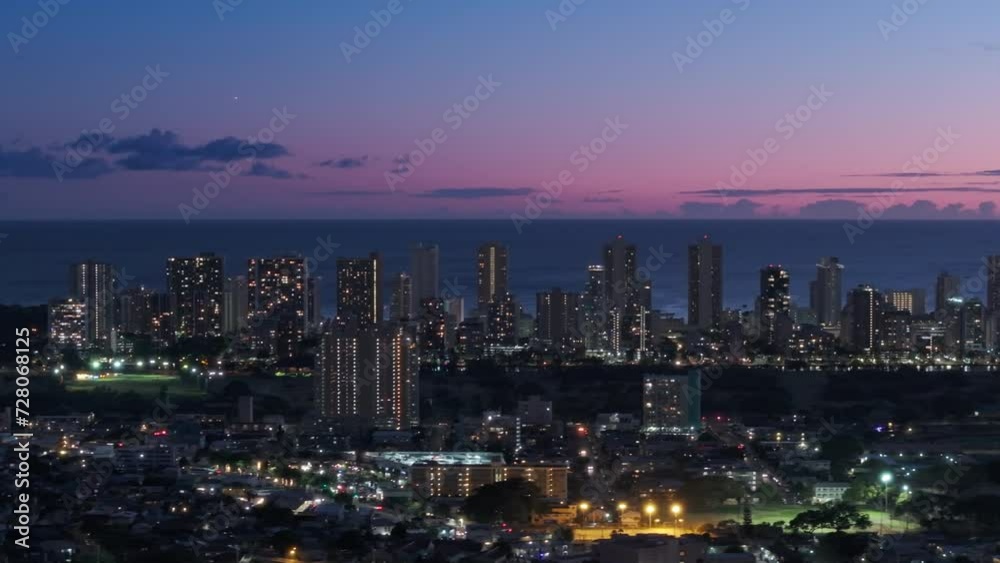 Downtown Waikiki sunset views. Cinematic aerial above Honolulu capital of Hawaii state, USA. Scenic pink purple sunset sky above city illuminated at night. Modern cityscape of Oahu island in Pacific Downtown Waikiki sunset views. Cinematic aerial above Honolulu capital of Hawaii state, USA. Scenic pink purple sunset sky above city illuminated at night. Modern cityscape of Oahu island in Pacific