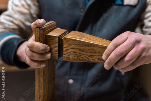 The carpenter glues the details of the cabinet leg photo