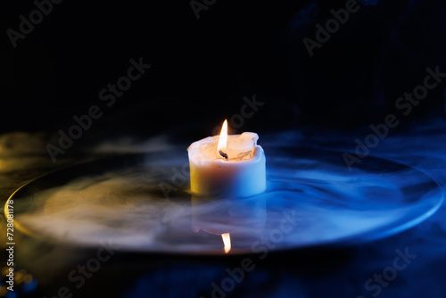 Candle in a bowl with a magical liquid. Colored smoke moves beautifully against on a dark background. Fortune teller, mind power, prediction, halloween concept.