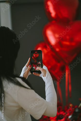 The girl is making shot of bright red balloons with heart shape for Valentine's day