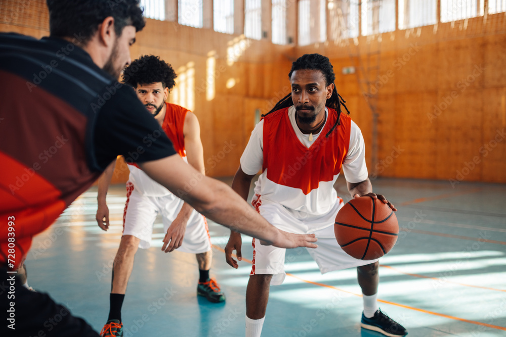 Naklejka premium Interracial basketball player is dribbling a ball on training.