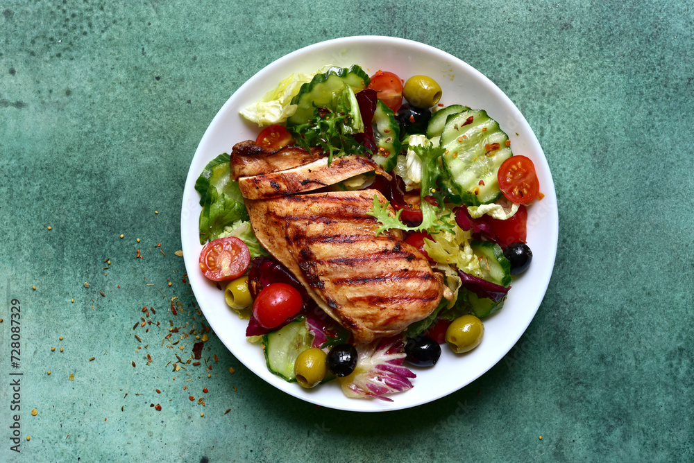 Grilled chicken fillet with fresh vegetable salad. Top view with copy space. Grilled chicken fillet with fresh vegetable salad. Top view with copy space.
