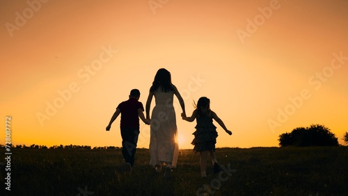 silhouette mother runs into sunset holding her son daughter hand  happy family running  boy girl  fun family activities active kids  dreams brought up  interest life  stage memory friendly relations