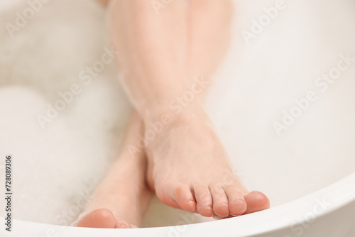Woman taking bath with foam in tub, closeup