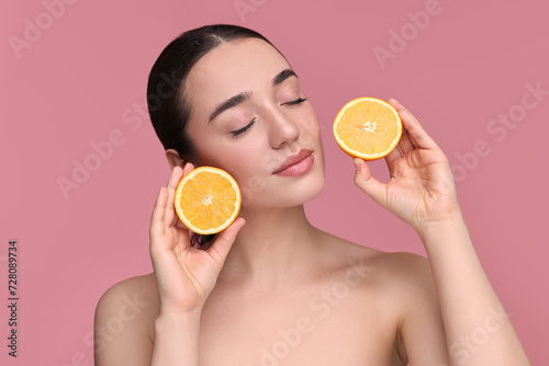 Beautiful young woman with pieces of orange on pink background