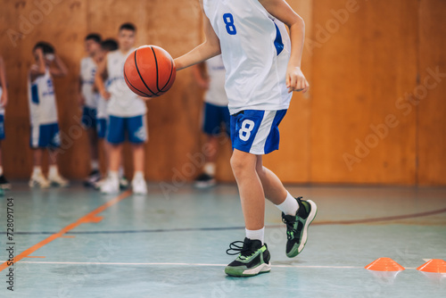 Cropped picture of a junior basketball player dribbling a ball on court.