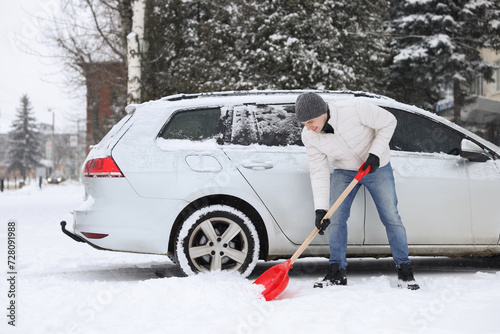 Man removing snow with shovel near car outdoors