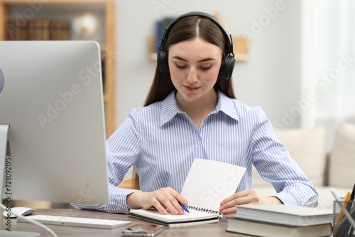 E-learning. Young woman taking notes during online lesson at table indoors
