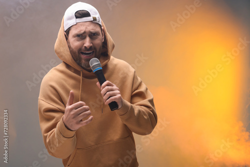 Singer with microphone rapping in color lights, space for text