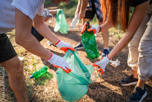 hands of unknown friends pick up waste garbage to clean forest photo