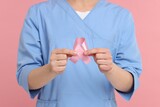 Mammologist with pink ribbon on color background, closeup. Breast cancer awareness