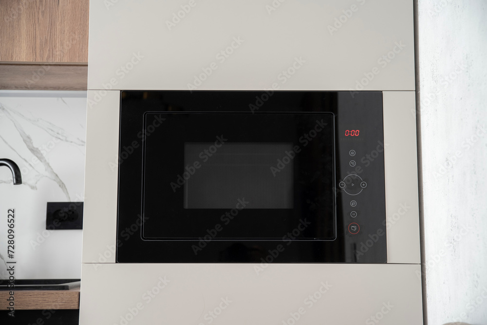 Fototapeta premium Black built-in microwave oven in kitchen furniture