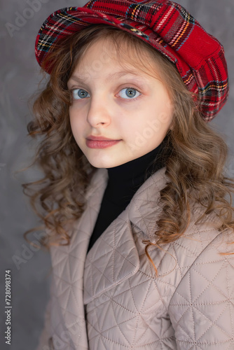 Photography a brown-haired girl with blue eyes and curly hair in a beige coat and a plaid ca