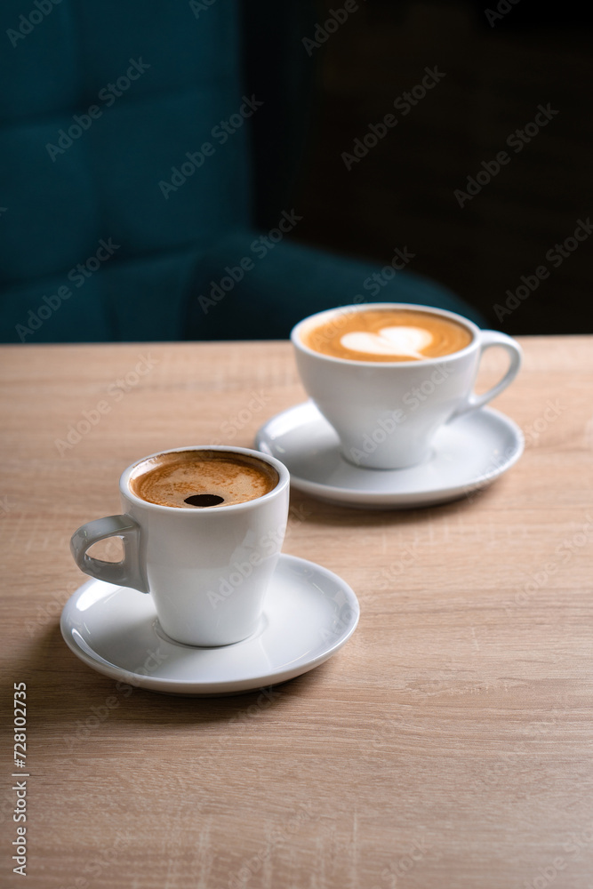 A cup of Americano and a cup of cappuccino on a light table in a cafe A cup of Americano and a cup of cappuccino on a light table in a cafe