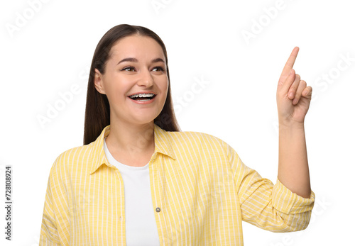 Smiling woman with dental braces pointing at something on white background