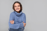 Smiling woman with dental braces in warm sweater on grey background. Space for text