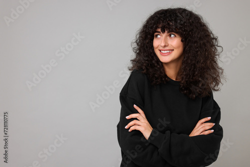 Happy young woman in stylish black sweater on light grey background, space for text