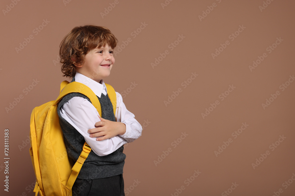 Happy schoolboy with backpack on brown background, space for text Happy schoolboy with backpack on brown background, space for text