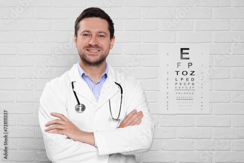 Ophthalmologist near vision test chart on white brick wall photo