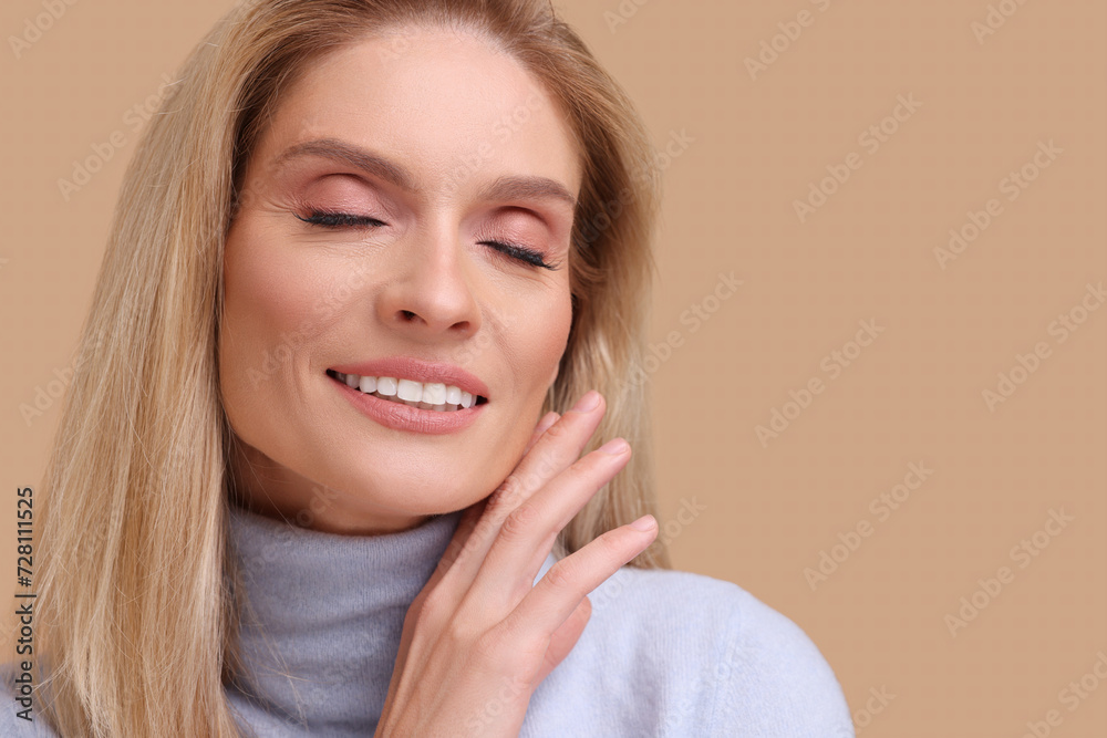 Portrait of smiling middle aged woman with blonde hair on beige background. Space for text Portrait of smiling middle aged woman with blonde hair on beige background. Space for text