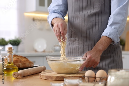 Making bread. Man preparing dough at wooden table in kitchen, closeup