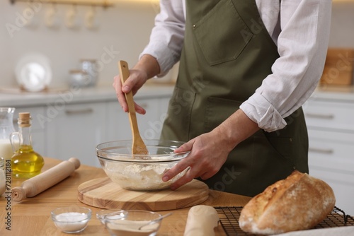 Making bread. Man preparing dough in bowl at wooden table in kitchen, closeup