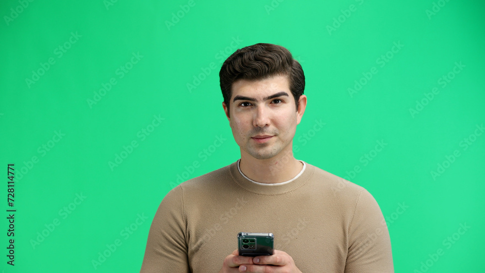 Man, close-up, on a green background, using a phone Man, close-up, on a green background, using a phone
