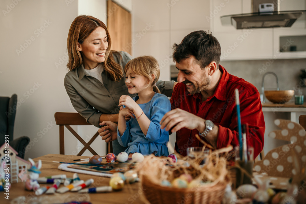 A family trio immersed in the Easter spirit, transforming plain eggs into works of art at the dining room table A family trio immersed in the Easter spirit, transforming plain eggs into works of art at the dining room table