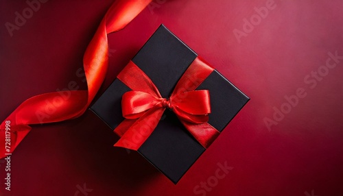 Black gift box decorated with red ribbon, view from above, isolated on red background, ideal for advertising products on Black Friday or Cyber Monday