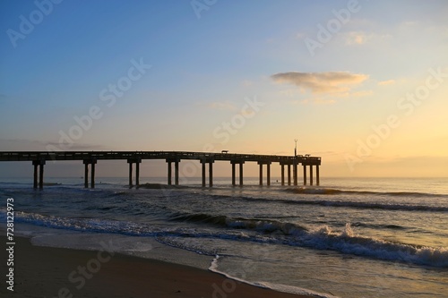 Sunrising over a pier and beach on the Atlantic Ocean