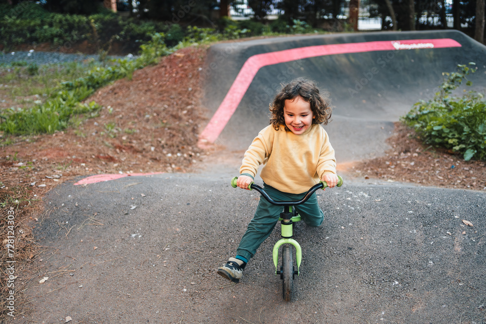 Fototapeta premium fashionable little boy having fun on pump track circuit with his bike