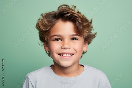 Portrait of a cute little boy with curly hair on a green background