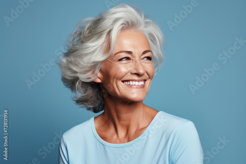 Mature woman with grey hair. Portrait of beautiful mature woman looking at camera and smiling while standing against blue background