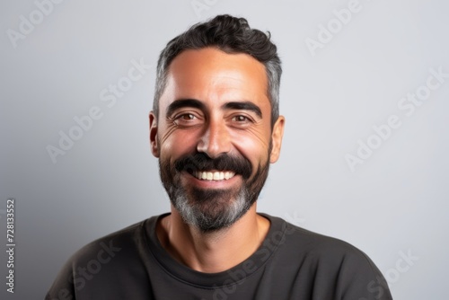 Handsome man with beard laughing and looking at the camera on a grey background