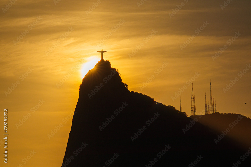 sun setting behind the statue of Christ the Redeemer in Rio de Janeiro ...