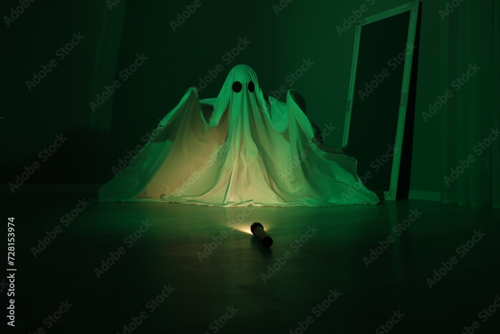 Creepy ghost. Woman covered with sheet in green light Creepy ghost. Woman covered with sheet in green light
