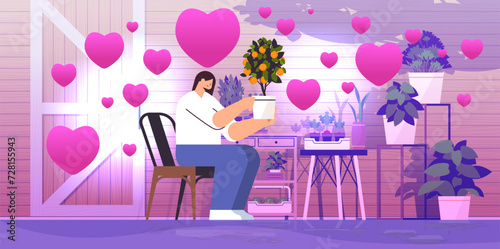 woman gardener taking care of potted orange plant at backyard home garden with pink love hearts happy valentines day celebration
