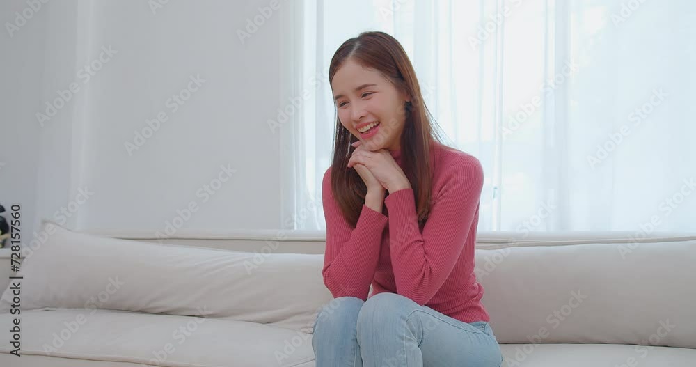Ecstatic young asian woman in pink turtleneck holding looking at a pregnancy test and surprise exciting reaction laughing smile with happiness on a white couch, celebrating good news, a moment of joy