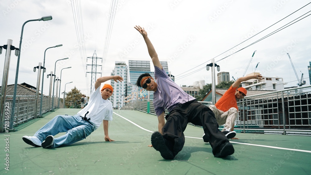 Group of professional break dancer dancing together or moving to hip hop music. Low angle camera of happy hipster team moving footstep and pose at camera. Crossing arm. Outdoor sport 2024. Sprightly.