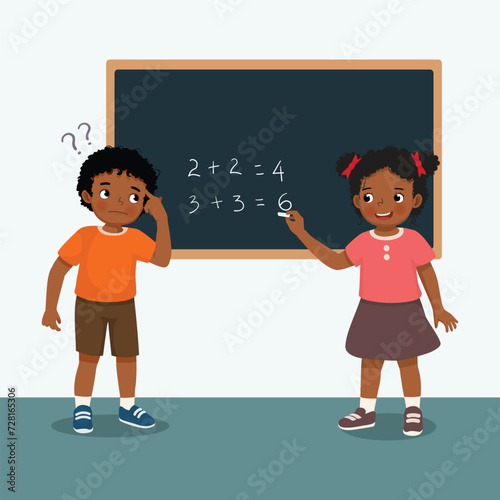 Cute little African kids student write on blackboard math equation in front of class with chalk