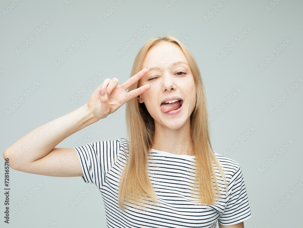 Young blond woman laugh and showing peace or victory sign at camera. Emotion and feelings. Young blond woman laugh and showing peace or victory sign at camera. Emotion and feelings.