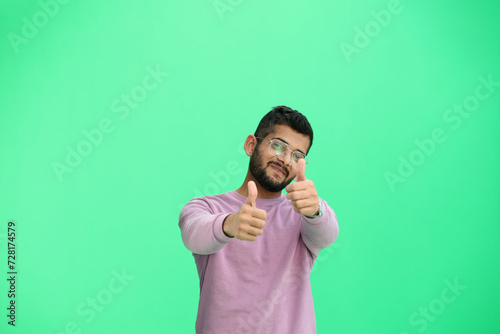 A man, on a green background, in close-up, shows his thumbs up photo