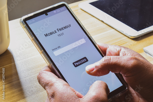 Person testing mobile friendliness tool to analyse the look and performance of his website on a mobile device. photo